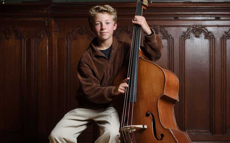 A young boy poses for a photo with his bass